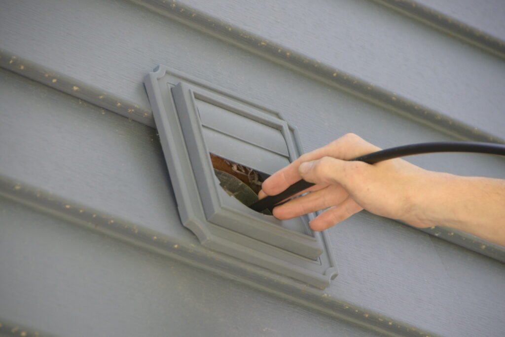 A small rod entering a dryer vent to clean the system